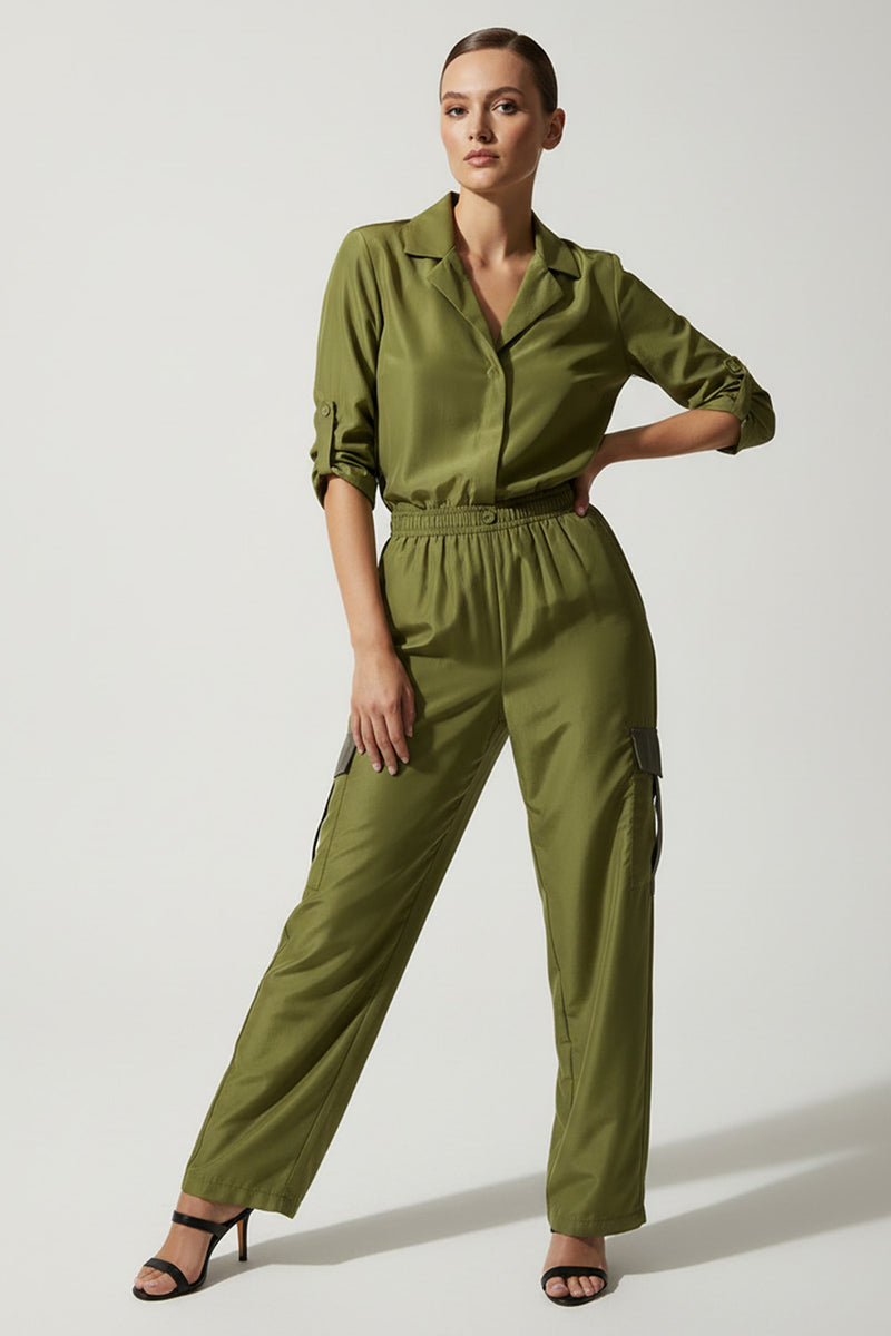 Πράσινη σατέν ολόσωμη φόρμα με ελαστική μέση και cargo λεπτομέρειες σε στούντιο φωτογράφιση.