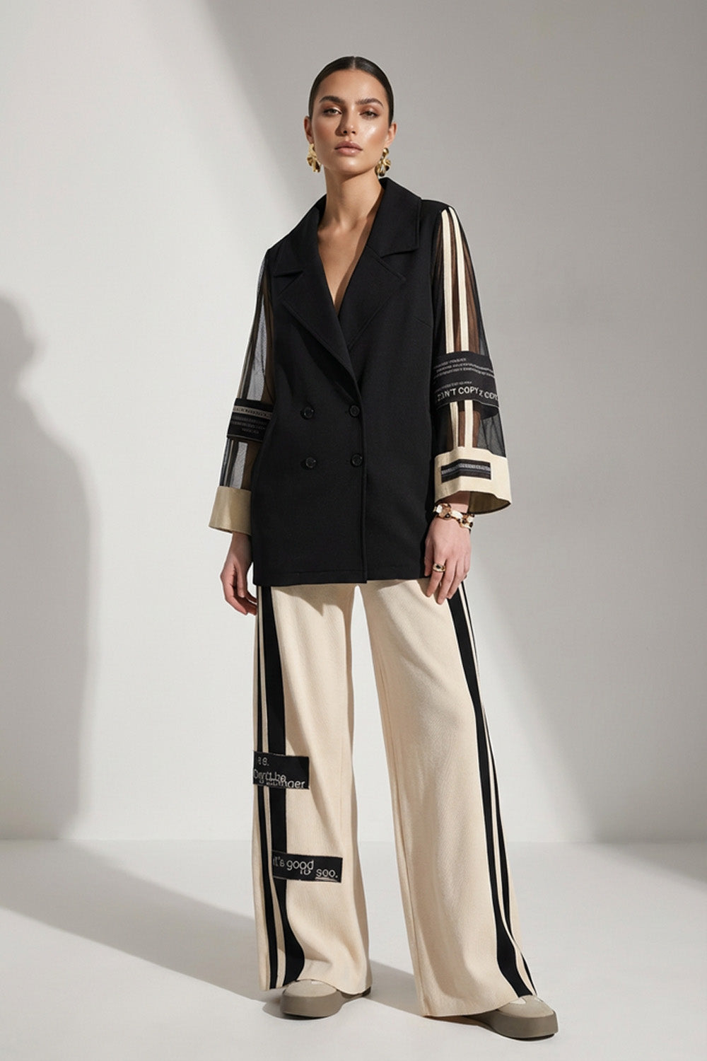 Γυναικείο σετ με μαύρο διπλόκουμπο σακάκι με διαφανή μανίκια και μπεζ παντελόνα με μαύρες ρίγες στο πλάι