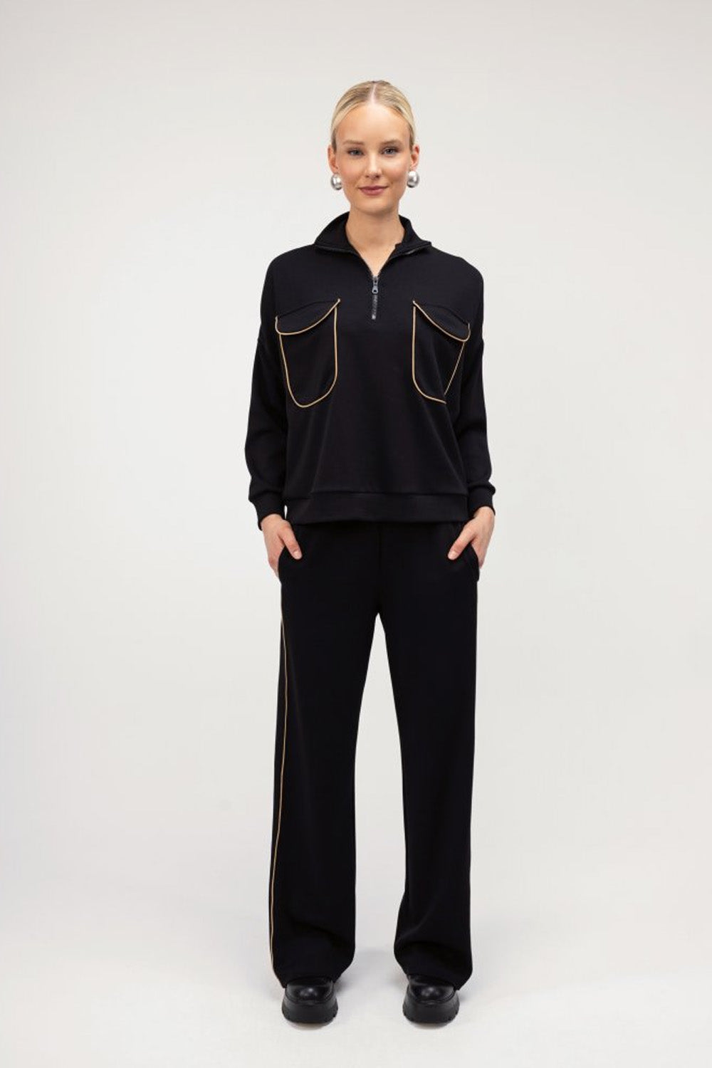 Μαύρο γυναικείο σετ με χρυσή ρέλι, μπλούζα με φερμουάρ και ίσιο παντελόνι σε άνετη γραμμή.