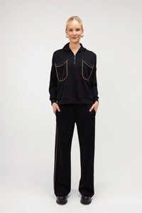 Μαύρο γυναικείο σετ με χρυσή ρέλι, μπλούζα με φερμουάρ και ίσιο παντελόνι σε άνετη γραμμή.