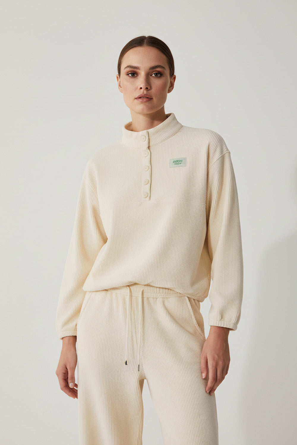 Γυναικείο rib σετ σε εκρού, με μπλούζα όρθιο γιακά και παντελόνι με λάστιχο και κορδόνι.