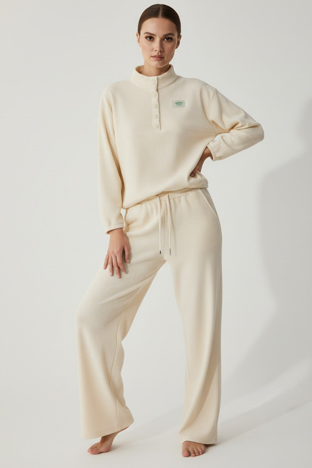 Γυναικείο rib σετ σε εκρού, με μπλούζα όρθιο γιακά και παντελόνι με λάστιχο και κορδόνι.