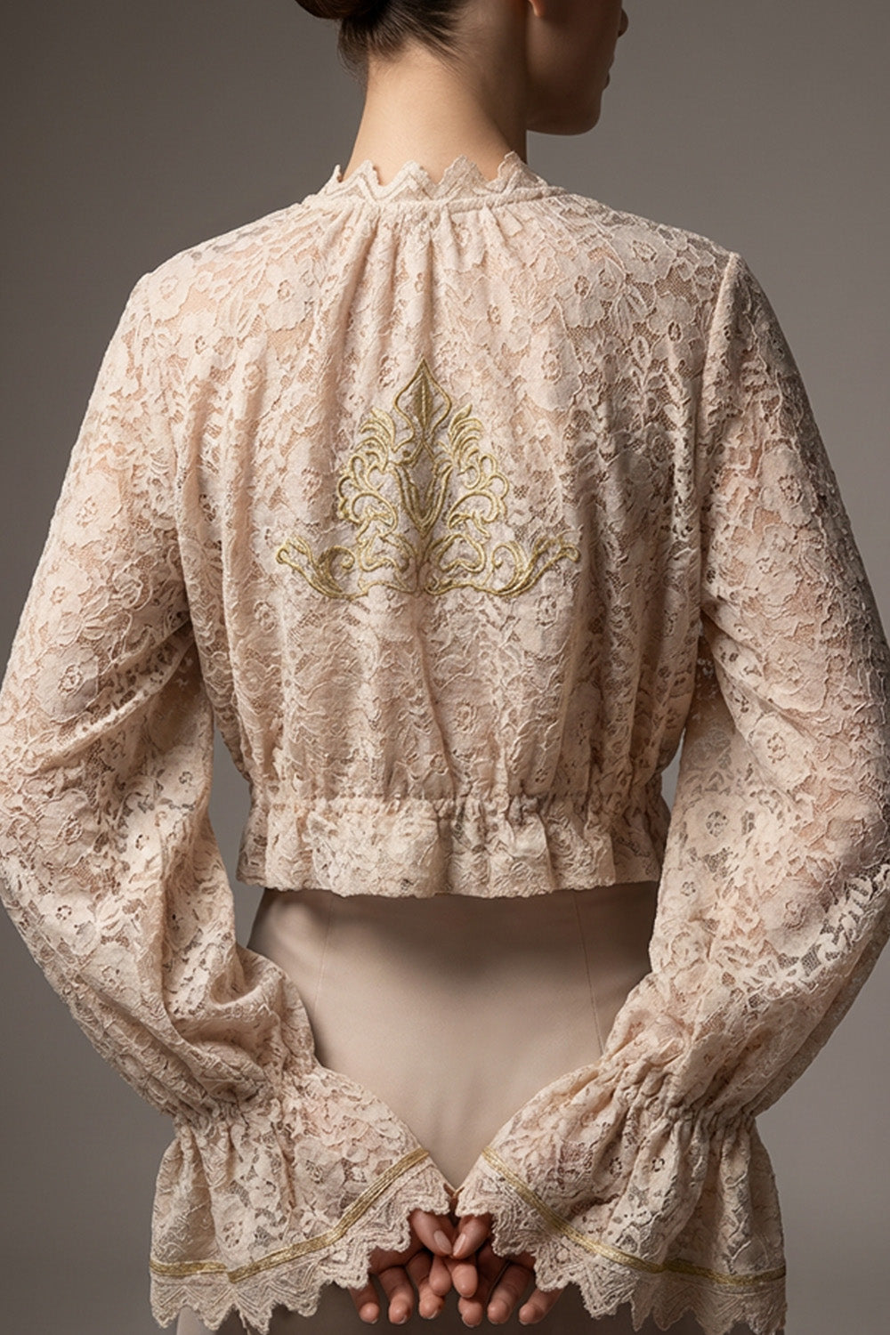 Εκρου δαντελένιο τοπ iRous με βολάν, μακριά μανίκια και χρυσό κέντημα στην πλάτη, φωτογράφιση σε στούντιο.