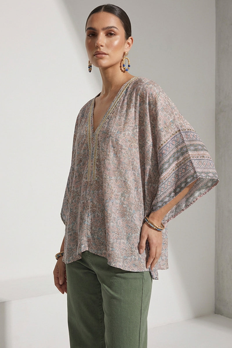 Γυναικεία εμπριμέ τουνίκ με V λαιμόκοψη και φαρδιά μανίκια, φορεμένη με πράσινο παντελόνι.