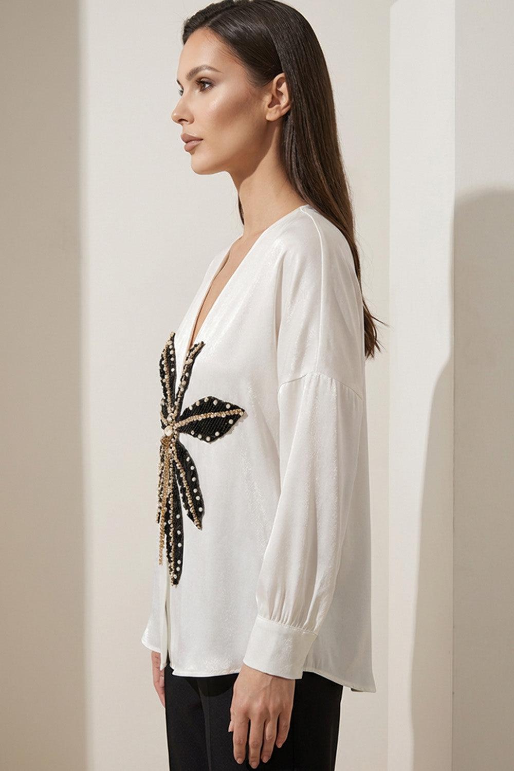 Εκρού γυναικεία βελούδινη μπλούζα με V λαιμό και διακοσμητικό μοτίβο σε μαύρο και χρυσό.