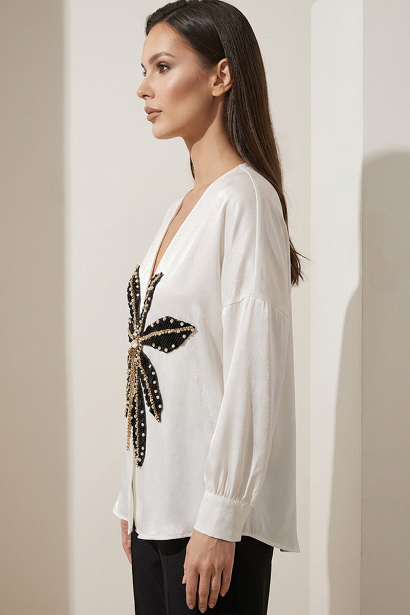 Εκρού γυναικεία βελούδινη μπλούζα με V λαιμό και διακοσμητικό μοτίβο σε μαύρο και χρυσό.