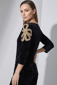 Μαύρη γυναικεία βελούδινη μπλούζα με V λαιμό και διακοσμητικό μοτίβο στον ώμο.