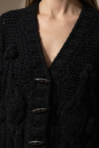 Χοντρή πλεκτή ζακέτα μαύρη με ανάγλυφη πλέξη, V λαιμόκοψη και κουμπιά, σε άνετη γραμμή για χειμερινά σύνολα.